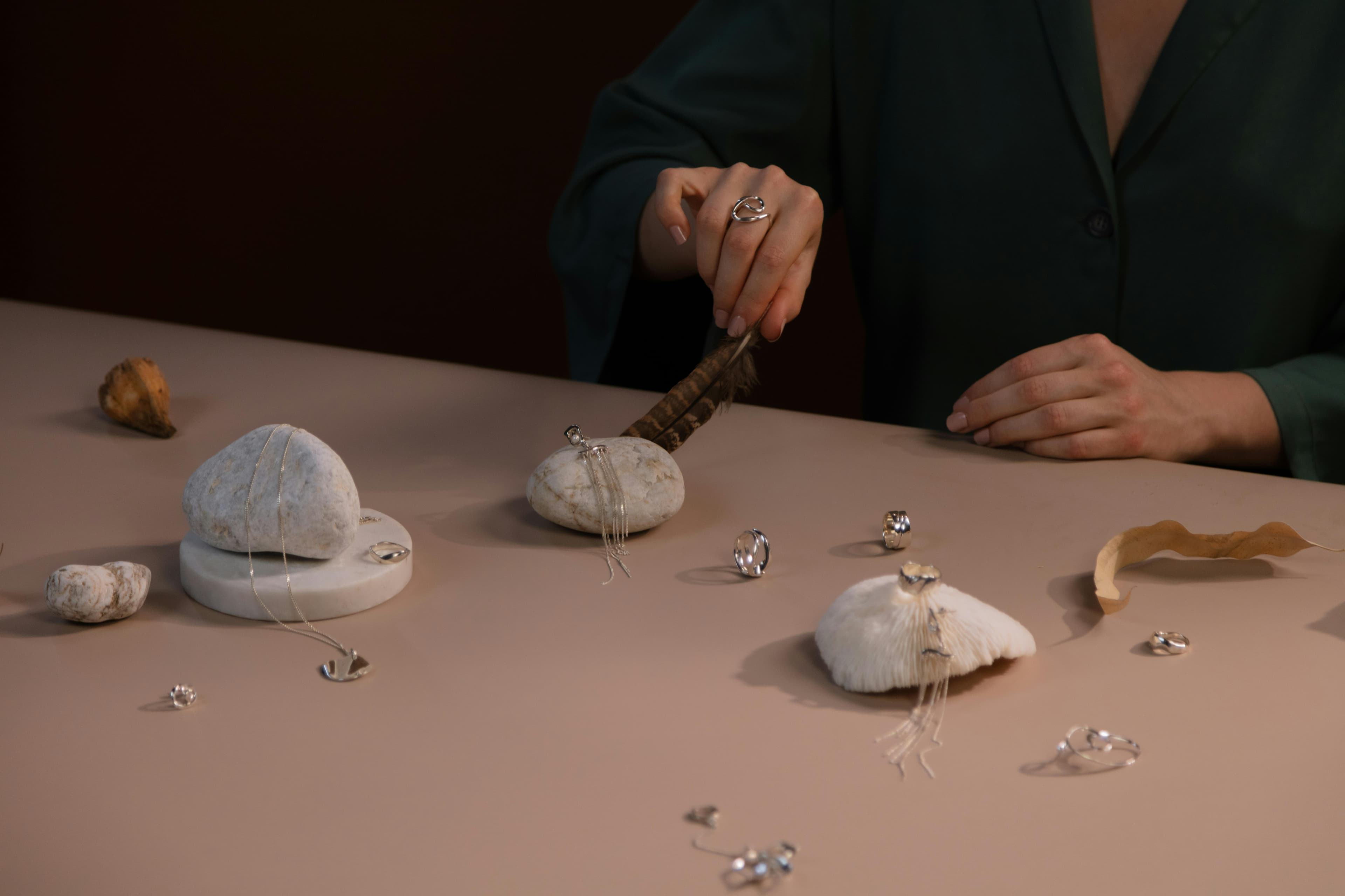 Styled silver jewelry arranged with stones on a muted set